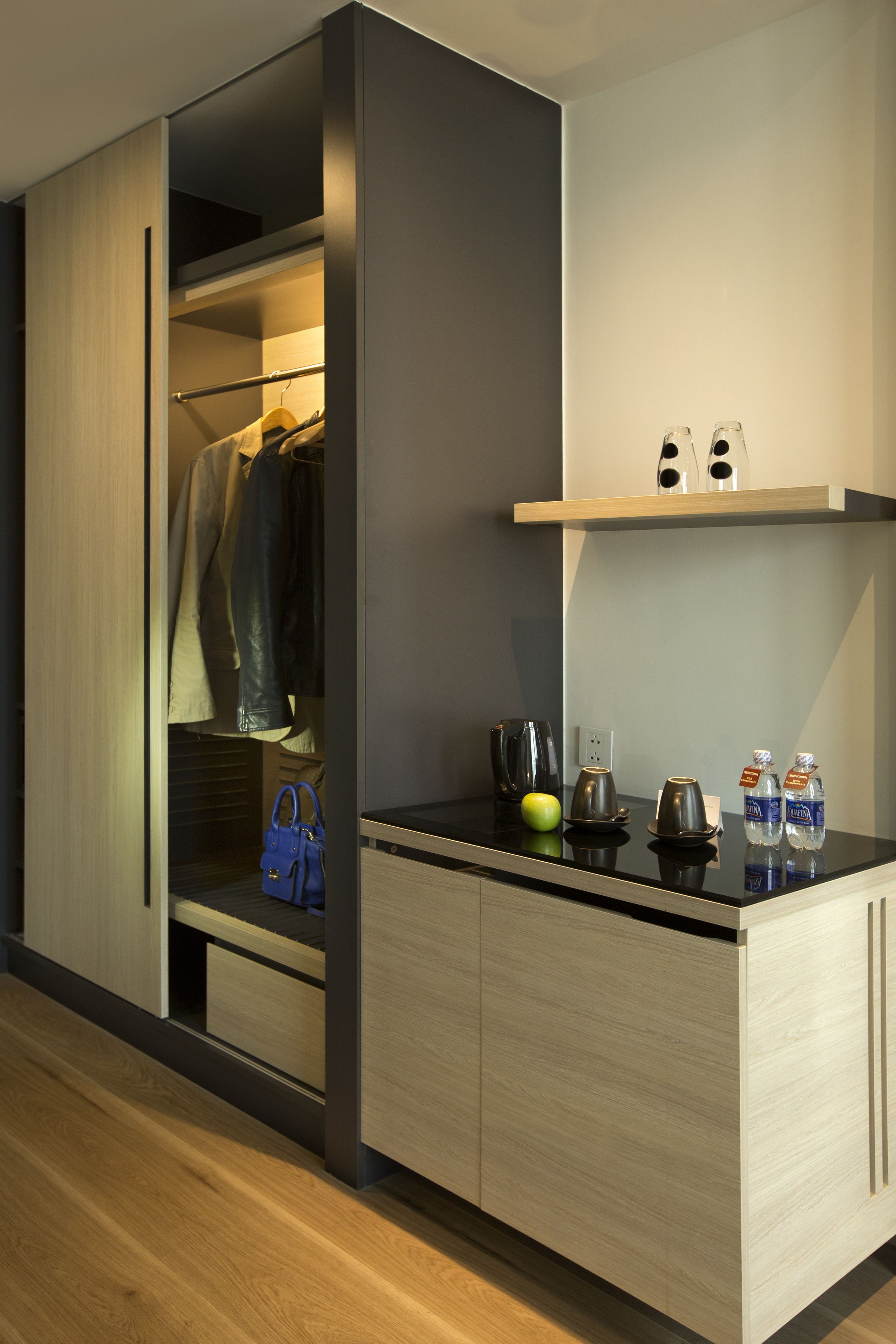 A modern kitchen with a built-in oven, a coffee maker, and a kettle on the countertop.