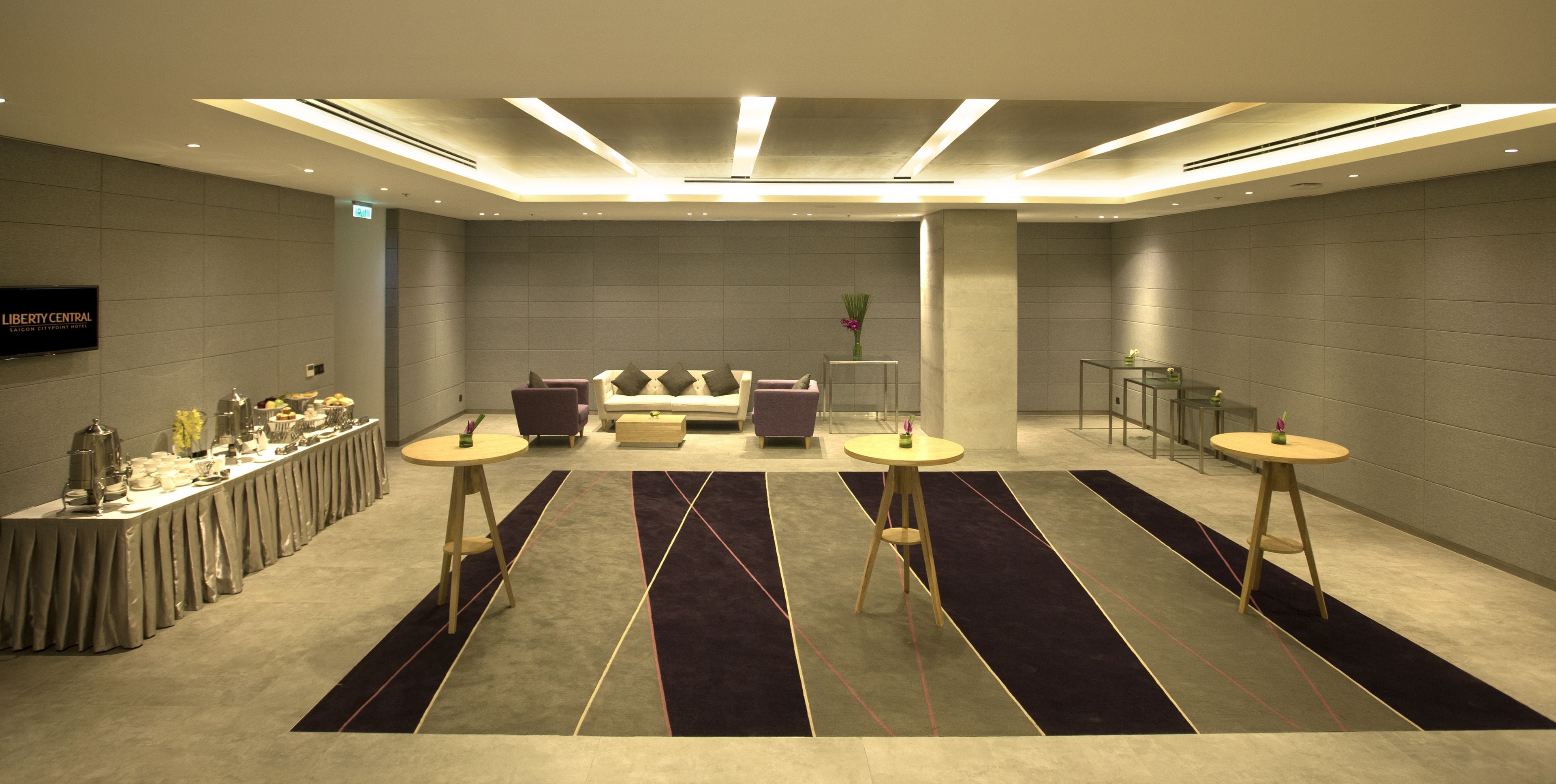Een moderne hotel lobby met een receptiebalie, een zithoek en een buffettafel.