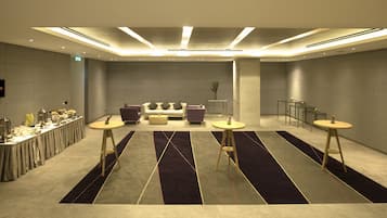 Een moderne hotel lobby met een receptiebalie, een zithoek en een buffettafel.
