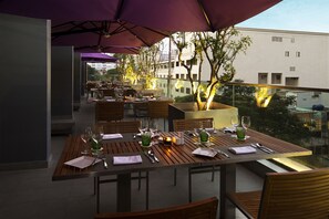 Enjoy a casual meal with a view at our outdoor dining area, featuring tables set with fine linens and glassware.
