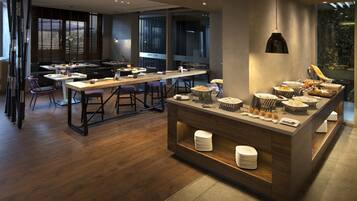A modern dining area with a long communal table, bar stools, and a buffet station.