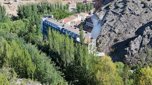 A hotel with a modern design, surrounded by a natural landscape with trees and rocky terrain. - Balneario Sicilia (Jaraba)