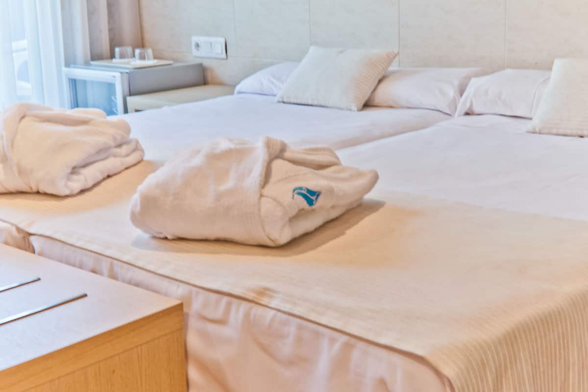 A hotel room with two beds, a bedside table, and a small desk.