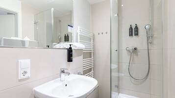 Een moderne badkamer met een wit wastafelmeubel, een glazen douchecabine en een handdoekhouder.