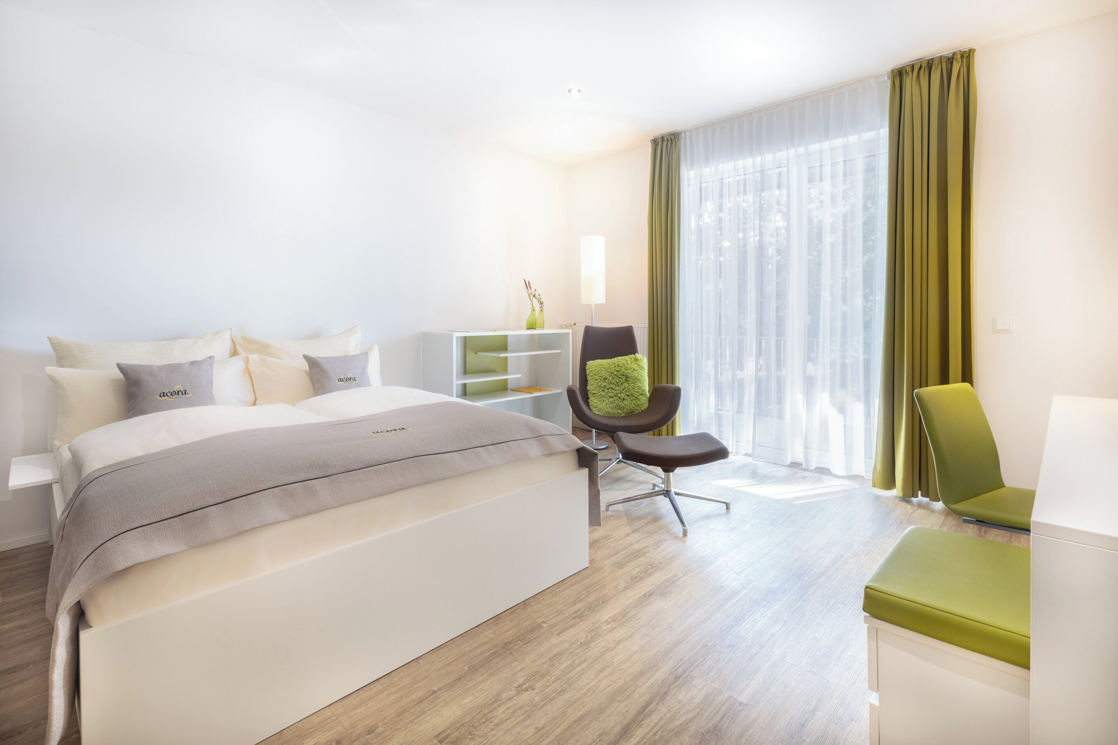 Et moderne hotelværelse med en stor seng, et skrivebord, en stol og et vindue med gardiner.