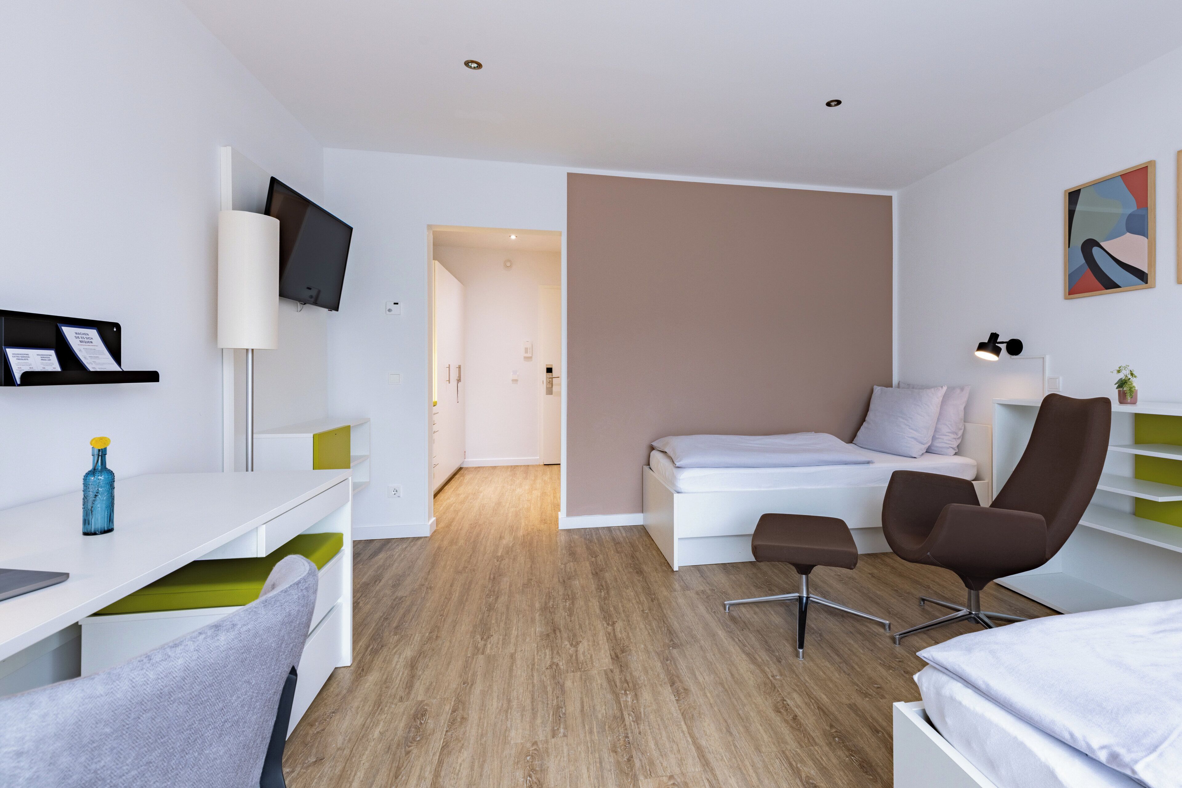 A modern hotel room with a bed, desk, chair, and a TV.