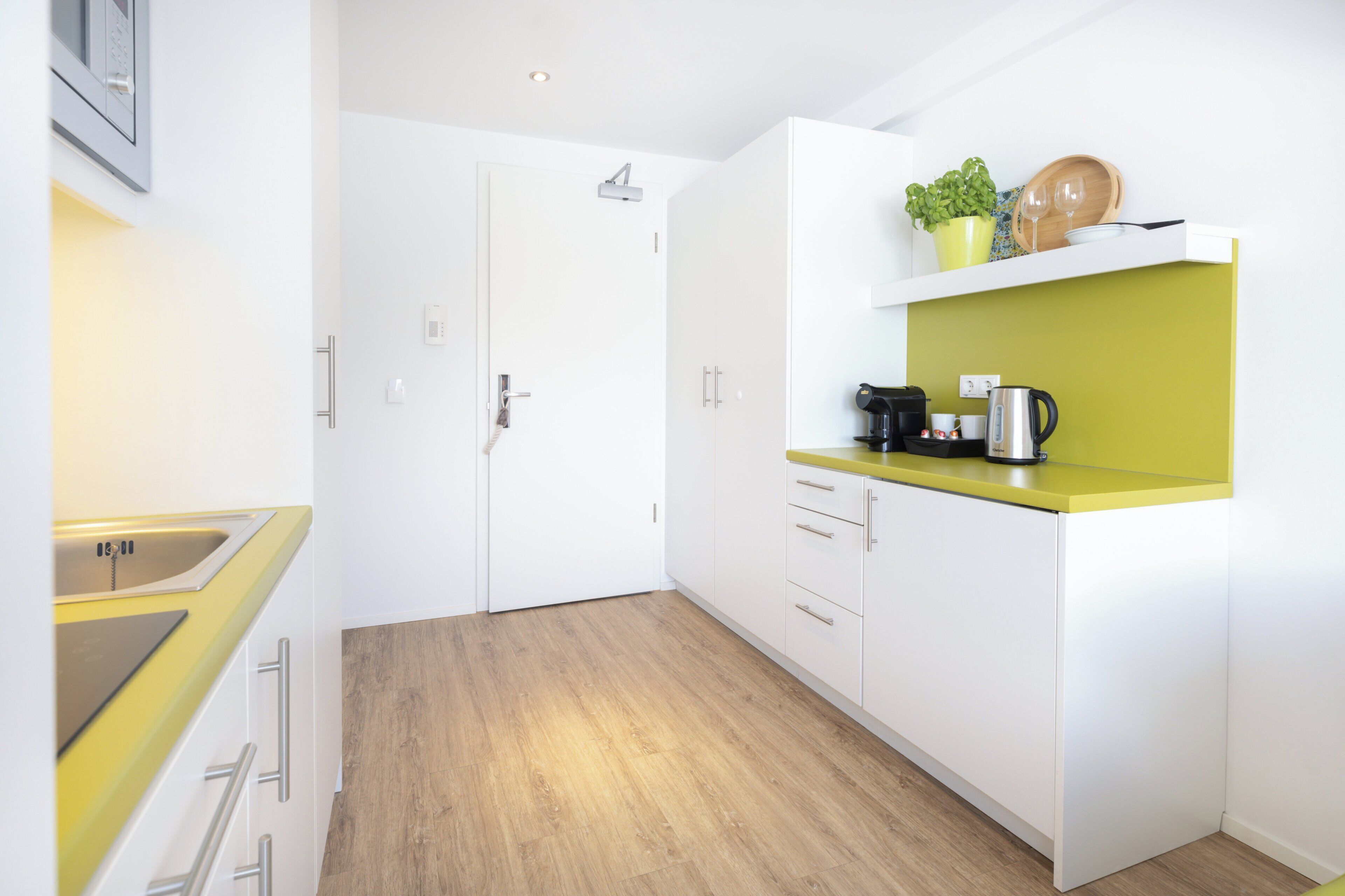 A modern kitchen with white cabinets, a yellow countertop, and a wooden floor.