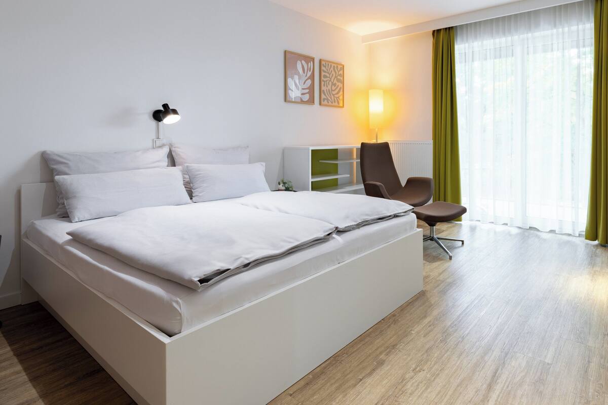 A modern hotel room with a large bed, a desk, and a chair.