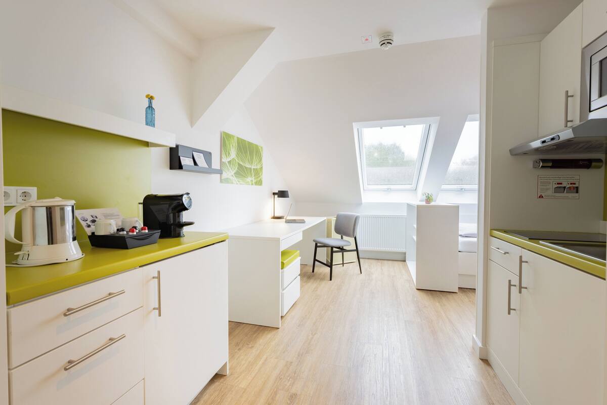 A modern kitchen with white cabinets, a yellow countertop, and a window providing natural light.