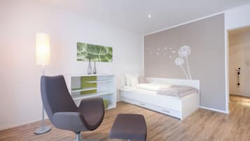 A modern bedroom with a bed, a chair, a desk, and a lamp.
