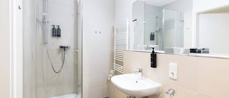 Un bagno moderno con doccia vetrata, lavandino bianco e uno specchio grande.