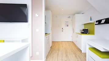 Une cuisine moderne avec des meubles blancs, un téléviseur noir et un plancher en bois.