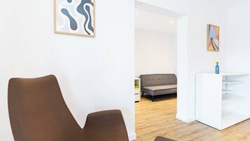 A modern living room with a brown sofa, a white console table, and abstract wall art.