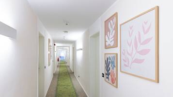 A hallway with framed artwork on the walls, carpeted flooring, and white walls.