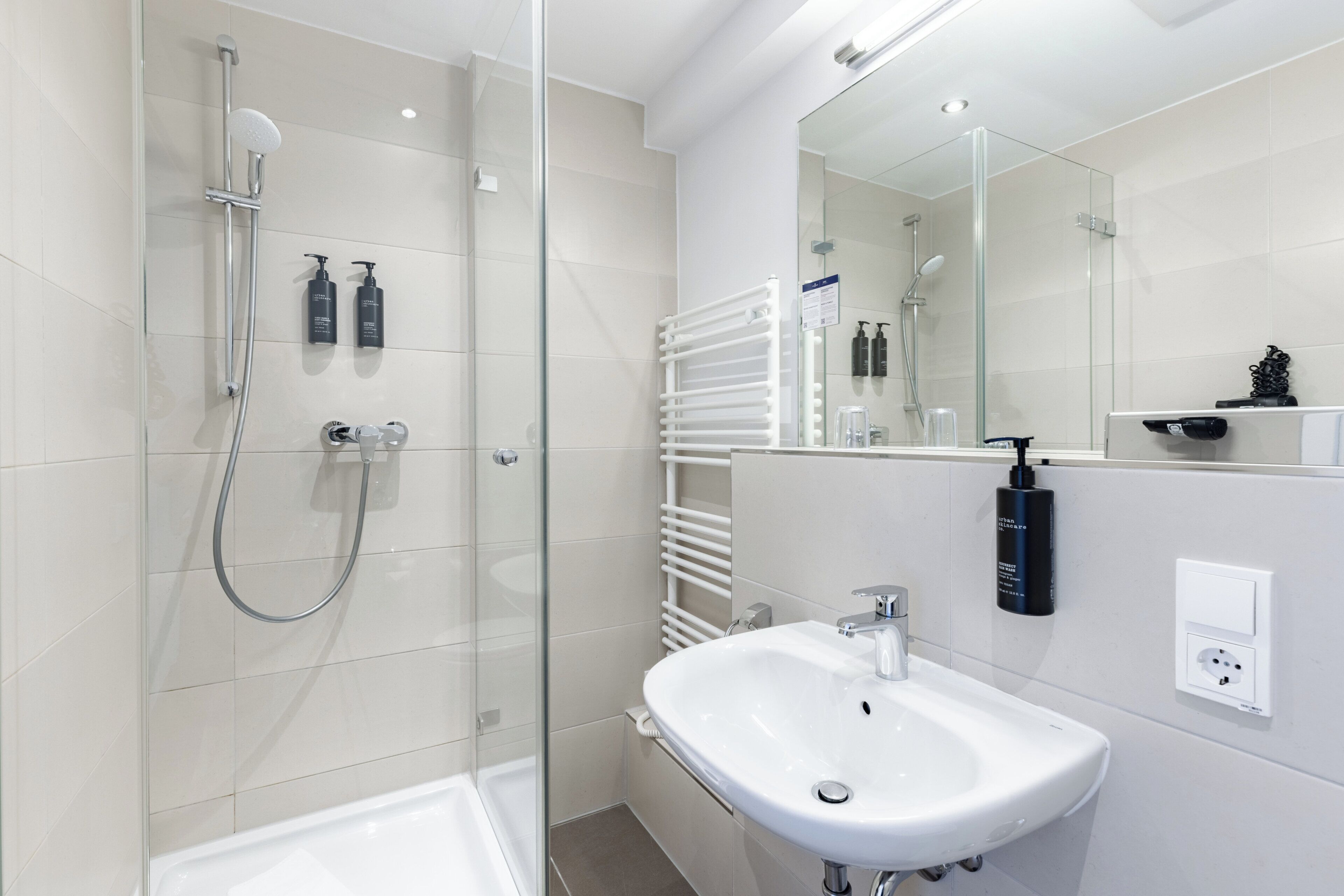 Een moderne badkamer met een douchecabine van glas, een wit wastafelmeubel en een grote spiegel.