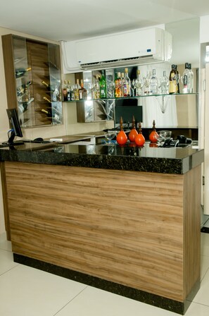 Una cocina moderna con una isla de madera, electrodomésticos de acero inoxidable y una vitrina de vidrio con varias botellas.