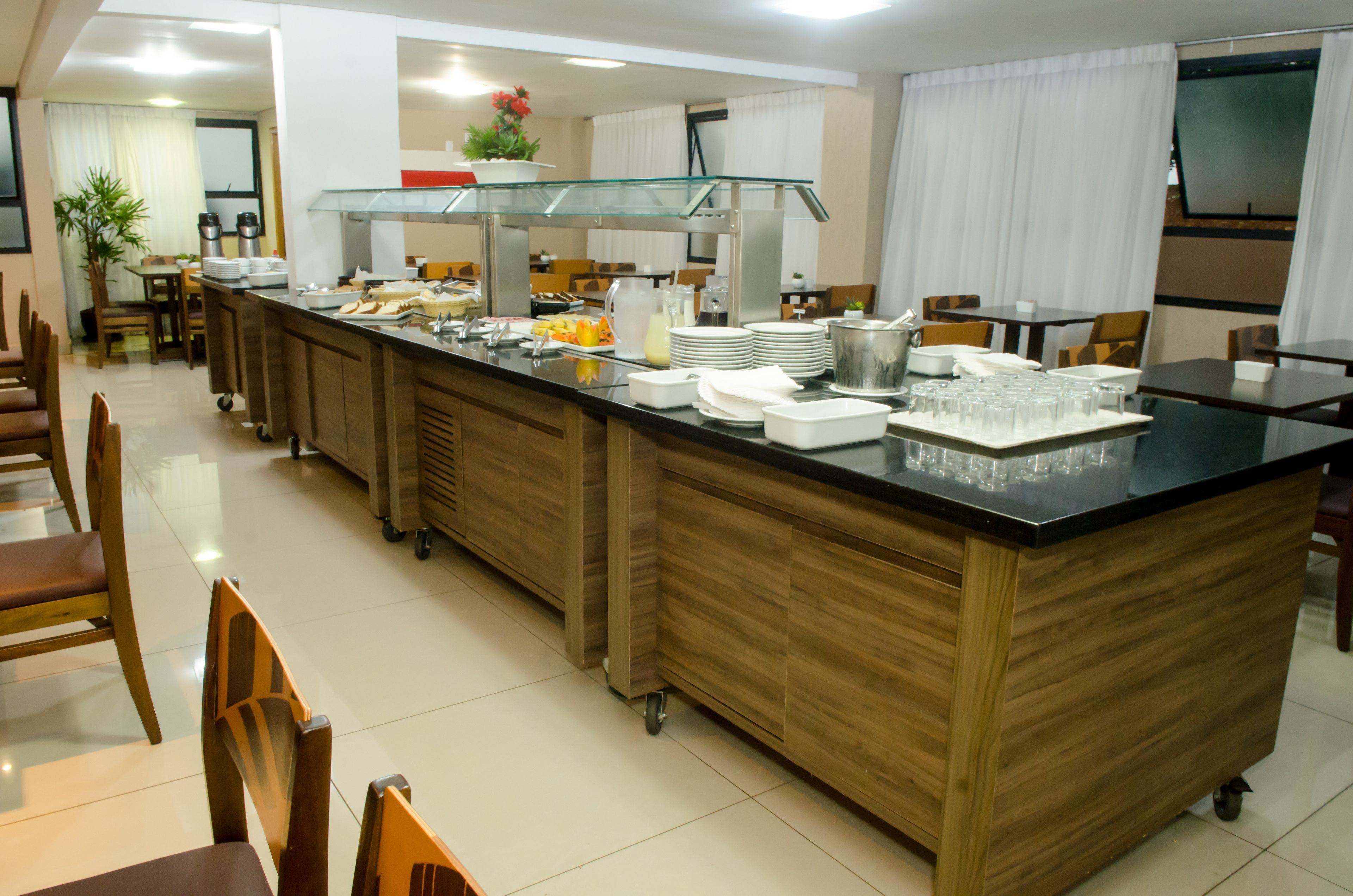 Montaje tipo bufé con una isla central, zona de servicio y mesas de comedor con sillas.