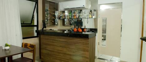 Una cocina compacta con una isla de madera, un comedor con mesa y sillas, y una unidad de aire acondicionado instalada sobre la encimera.