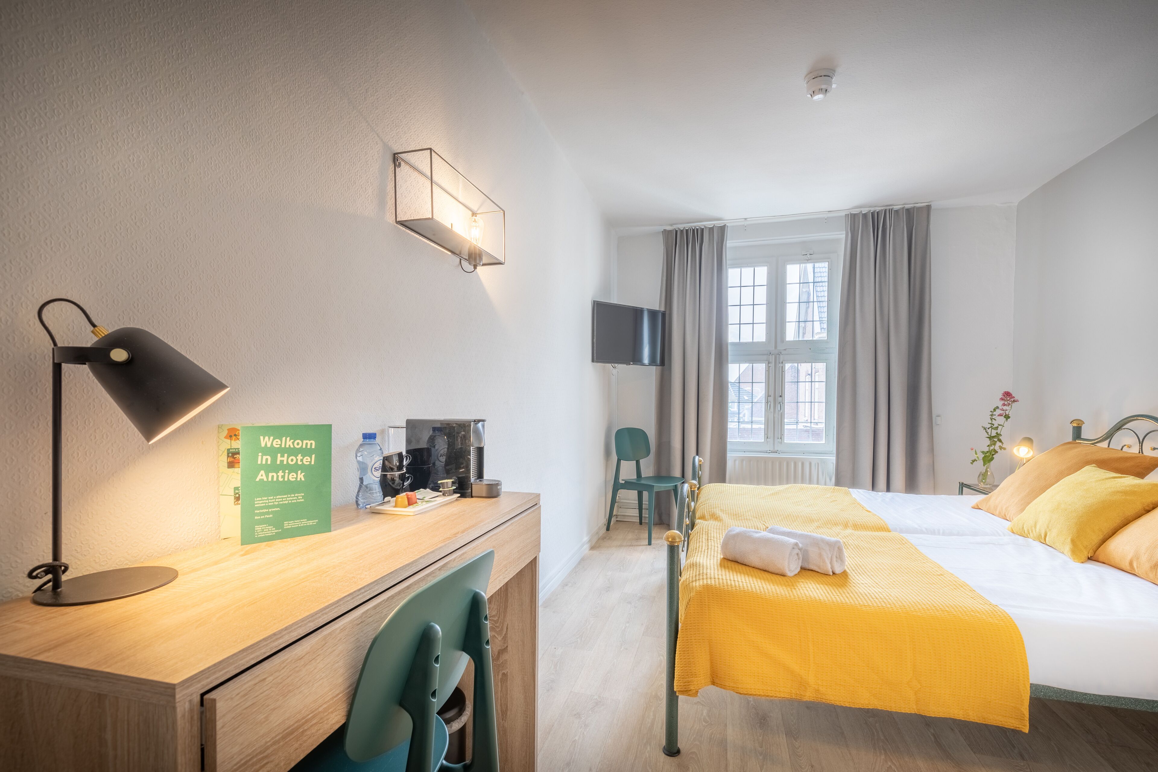 Een hotelkamer met een bed, bureau, stoel en een televisie.