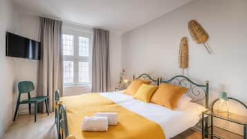 A hotel room with a bed, a TV, a chair, and a window with curtains.