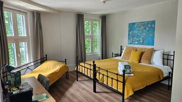 Een kamer met een bed, een bureau en een raam.