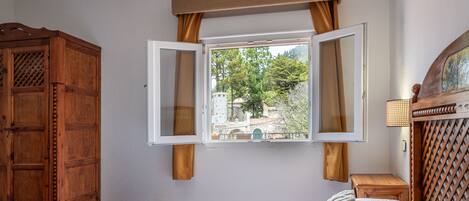 Un dormitorio con una cama, un armario y una ventana con cortinas.