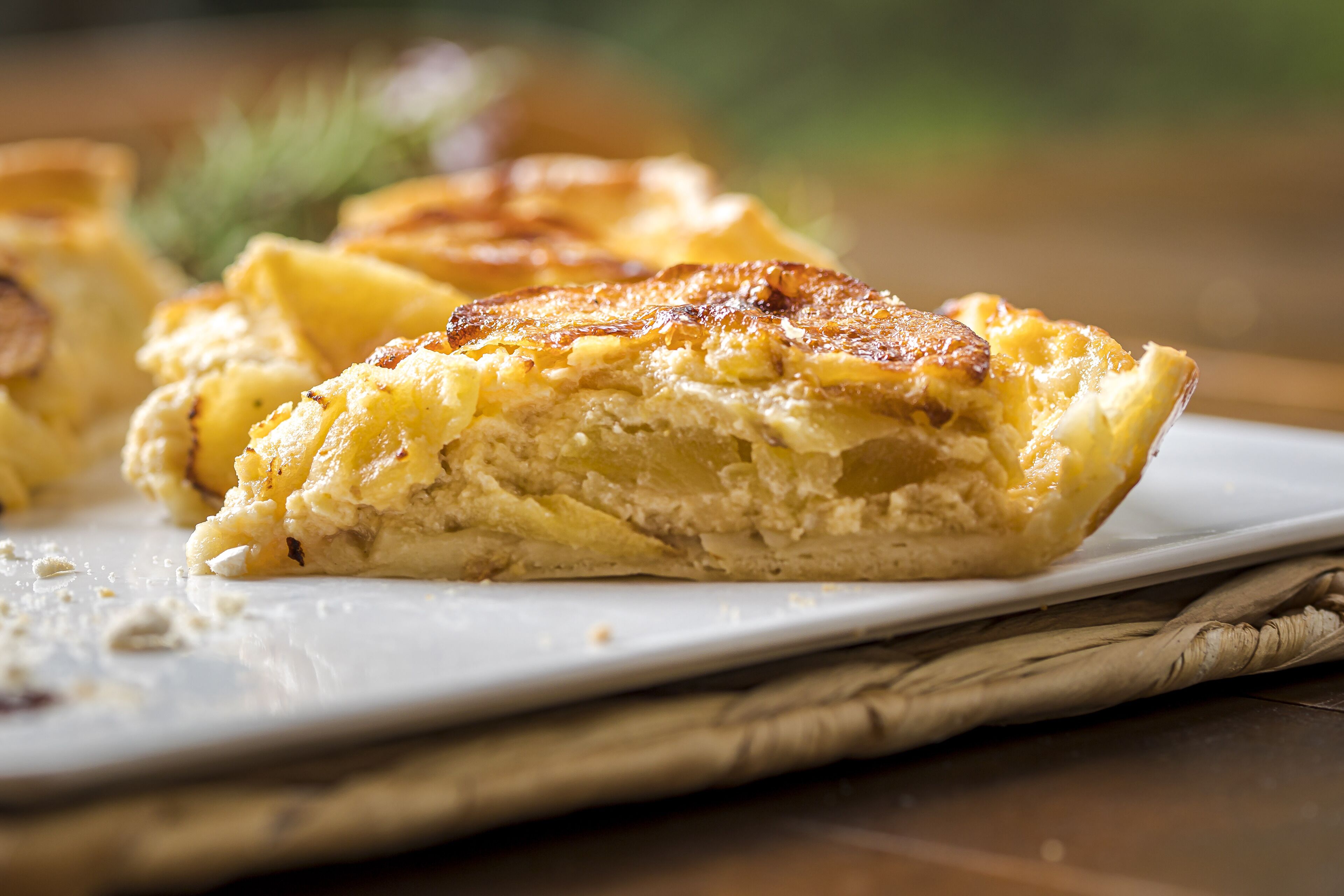 Een close-up van een gebakken gerecht met een goudbruine korst, mogelijk een hartige taart of hartige pastei, op een wit bord.