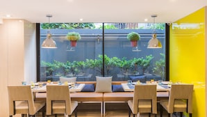 A dining area with a long table, multiple chairs, and hanging pendant lights. - Alt Hotel Nana by UHG (Bangkok)