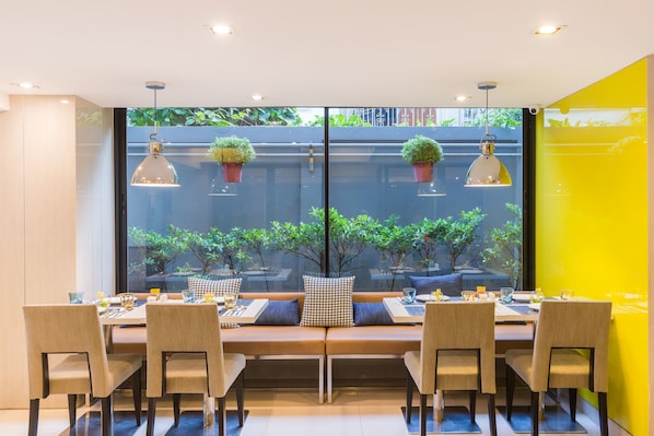A dining area with a long table, multiple chairs, and hanging pendant lights.