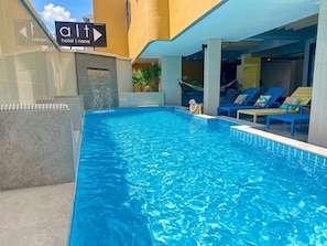 Une piscine équipée de chaises longues et d’un panneau indiquant son emplacement.