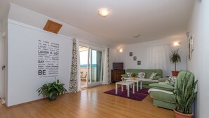 A modern living room with a green sofa, a small white table, and a potted plant. - Apartments Vojin (Okrug)