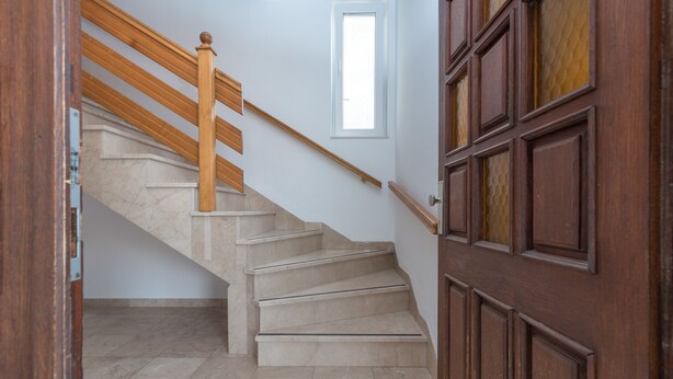 A staircase with wooden handrails and beige steps leading to a door with a glass panel. - Apartments Vojin (Okrug)