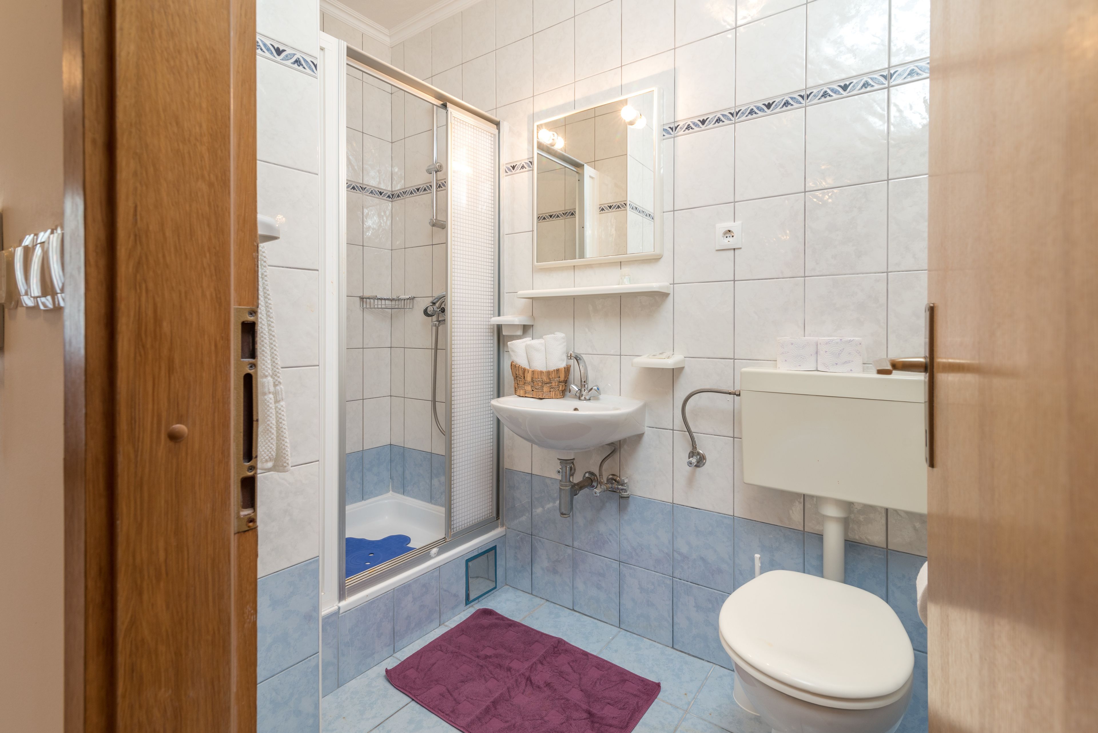 Een badkamer met douche, wastafel en toilet.