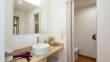 Een badkamer met een wit wastafel, een spiegel, een handdoekrek en een toilet.