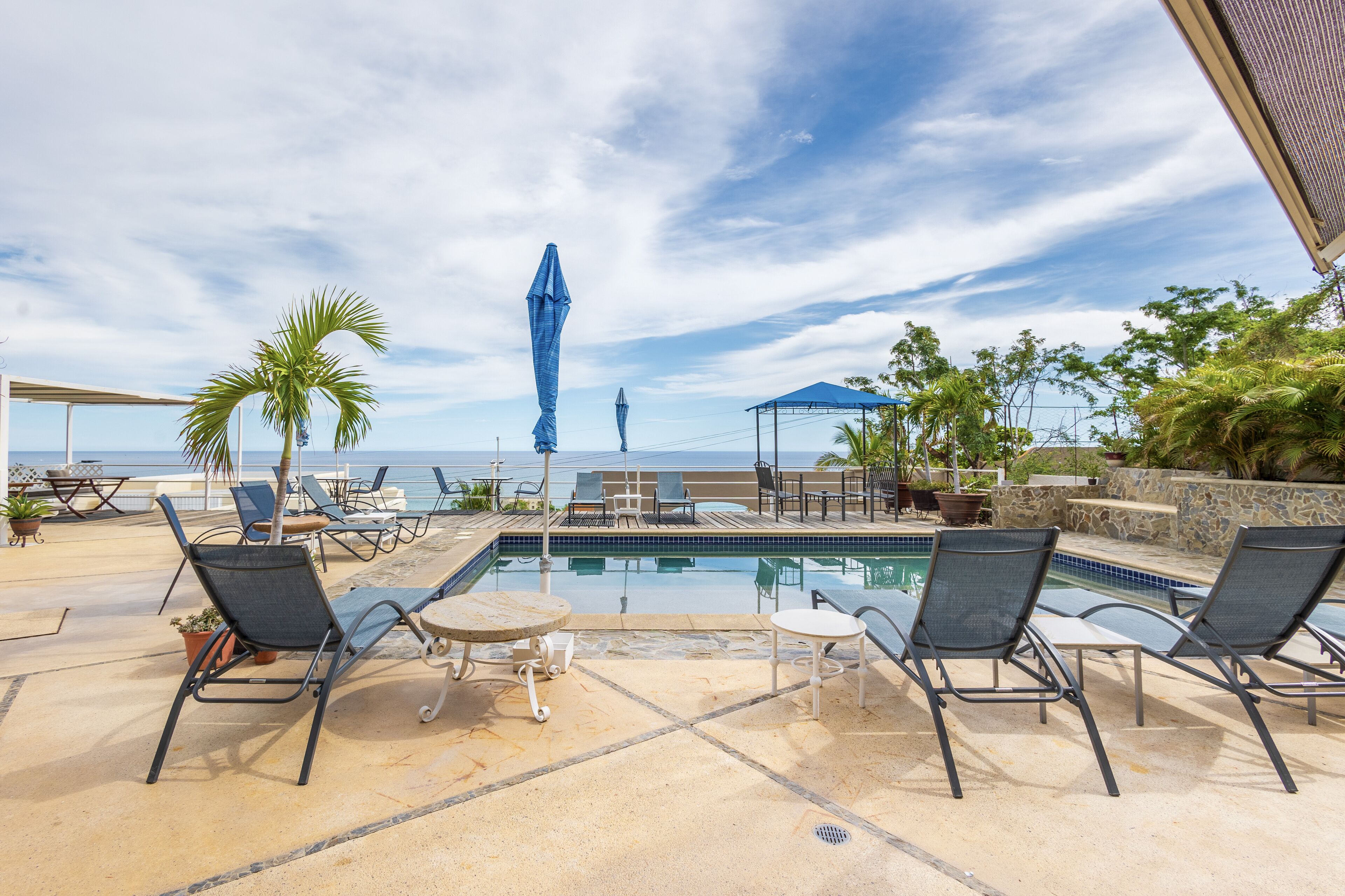 Un espace aménagé au bord de la piscine, avec des chaises longues, une petite table et des parasols.