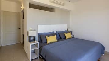 Un dormitorio moderno con una cama grande, mesitas de noche blancas y un ventilador de techo.