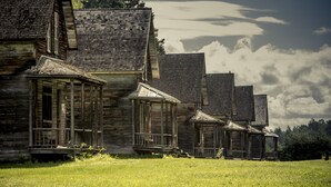 Une rangée de maisons rustiques en bois, dotées de toits à forte pente et d’un porche.