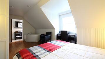 Une chambre à coucher avec un grand lit, un bureau, une chaise, une baignoire et une salle de bain équipée d’un lavabo et d’un miroir.
