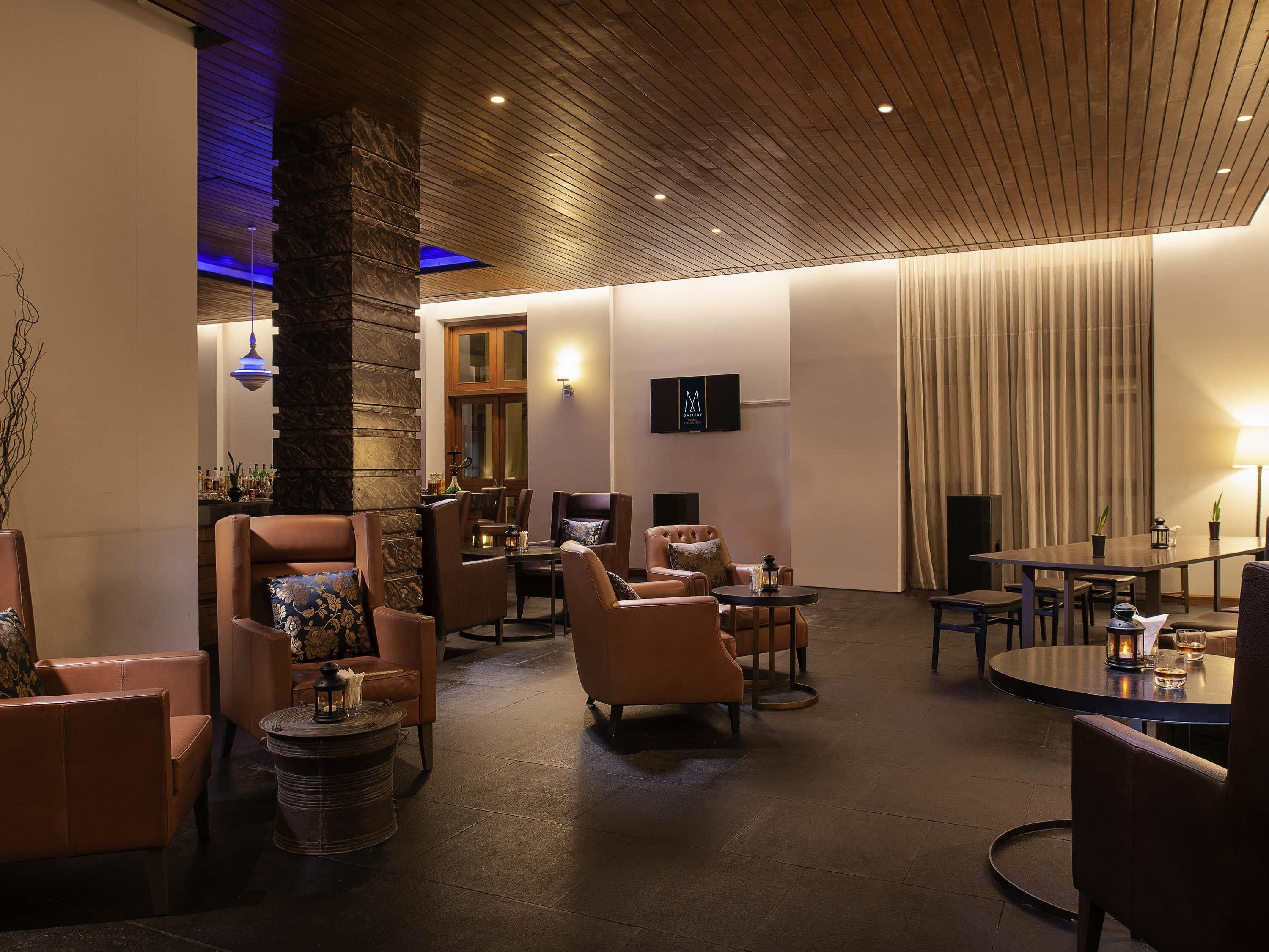 Ein stilvoller Lounge-Bereich mit Ledersofas, einem runden Tisch und einer Bar mit Flaschen.