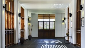 A hallway with a wooden door, a large vase, and a small table. - The Lake Garden Hotel Nay Pyi Taw - MGallery Collection (Naypyidaw)