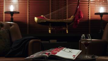 A dimly lit room with a harp, a glass of red wine, and an open magazine on a table.