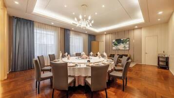 A dining area with a round table, chairs, and a chandelier.