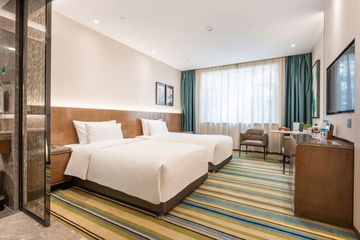 Ein Hotelzimmer mit zwei Betten, einem Schreibtisch und einem Stuhl.