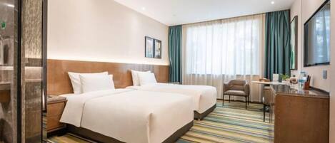 A hotel room with two beds, a desk, and a chair.