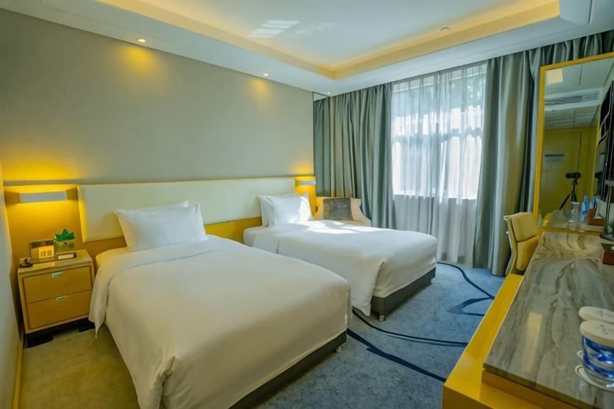 Habitación de hotel con dos camas, un escritorio y un espejo.