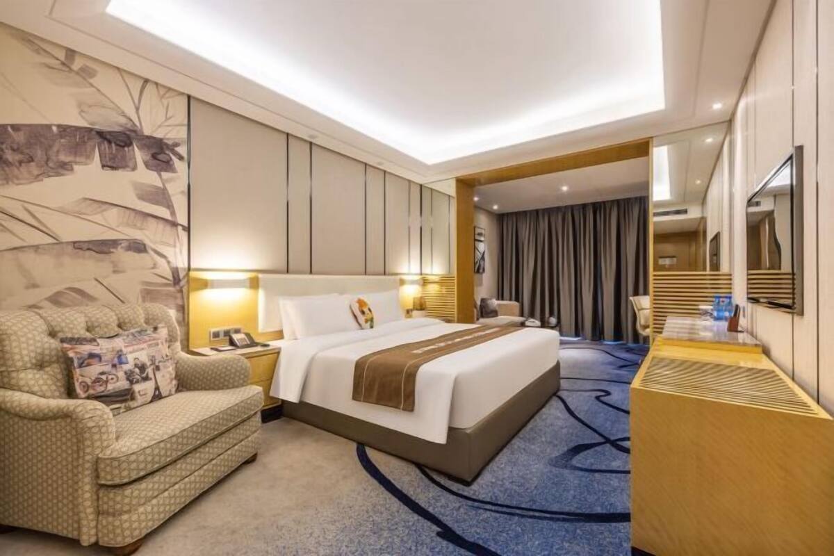 Una habitación de hotel con una cama grande, un sofá, un escritorio y un espejo.