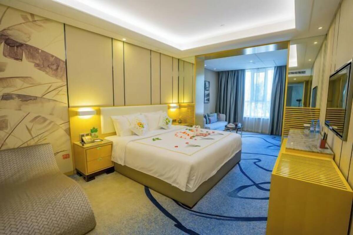 Una habitación de hotel con una cama grande, mesitas de noche, un escritorio y un espejo.