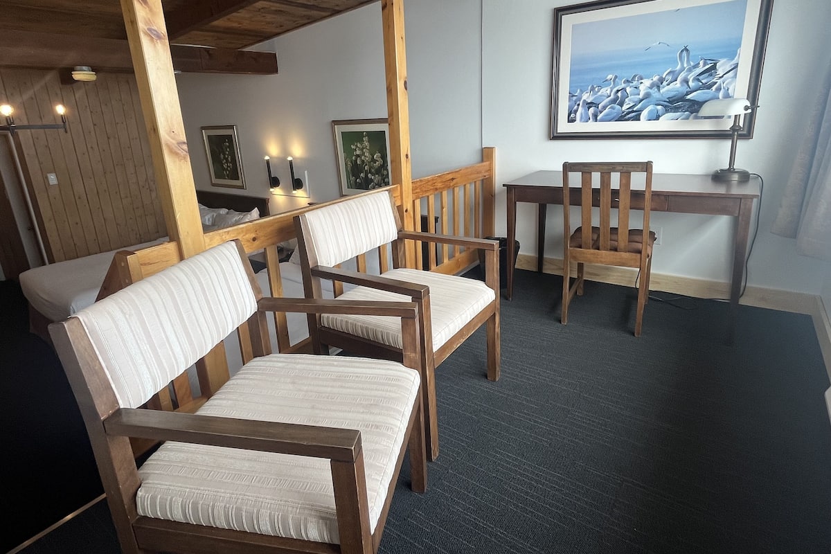 A cozy room with wooden furniture, a desk, and a framed painting of birds.