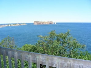 A coastal view with a wooden railing, clear blue sea, and rocky cliffs. - Hôtel Motel La Côte Surprise (Perce)