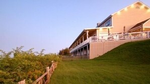 A large, multi-story building with a sloped roof, a covered porch, and a well-maintained lawn. - Hôtel Motel La Côte Surprise (Perce)